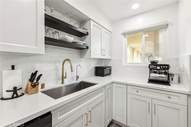 kitchen with sink, backsplash, white cabinets, and black dishwasher