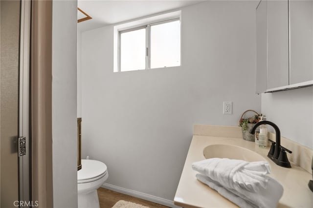 bathroom featuring wood finished floors, vanity, toilet, and baseboards