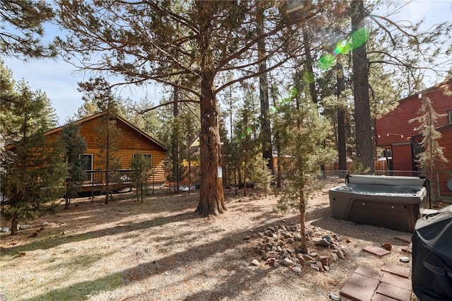 view of yard with a hot tub, fence, and a wooden deck