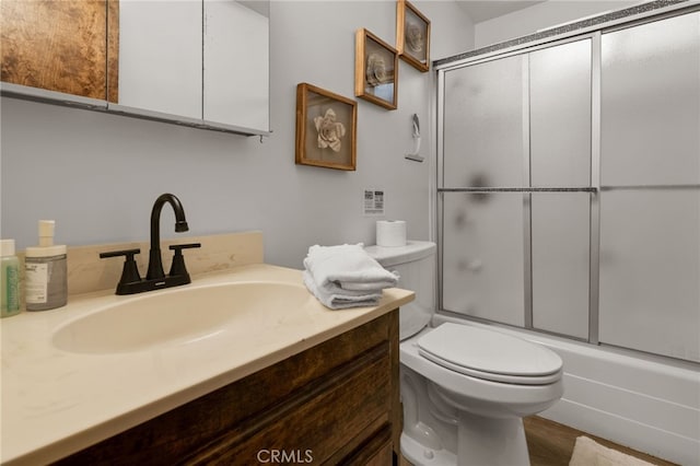 full bathroom with toilet, combined bath / shower with glass door, wood finished floors, and vanity