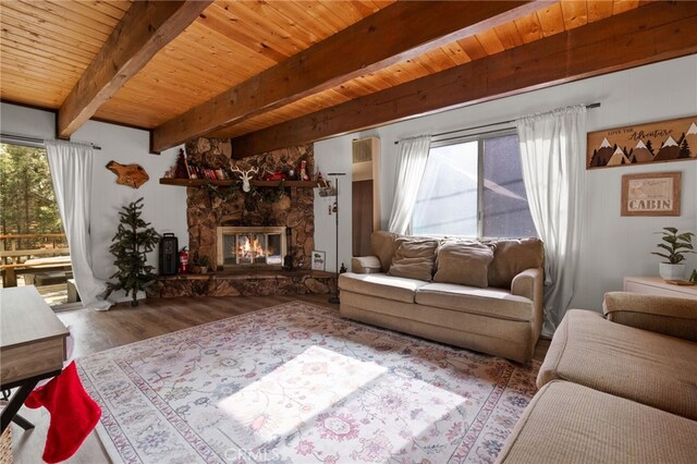 living room featuring beamed ceiling, wooden ceiling, a stone fireplace, and hardwood / wood-style flooring