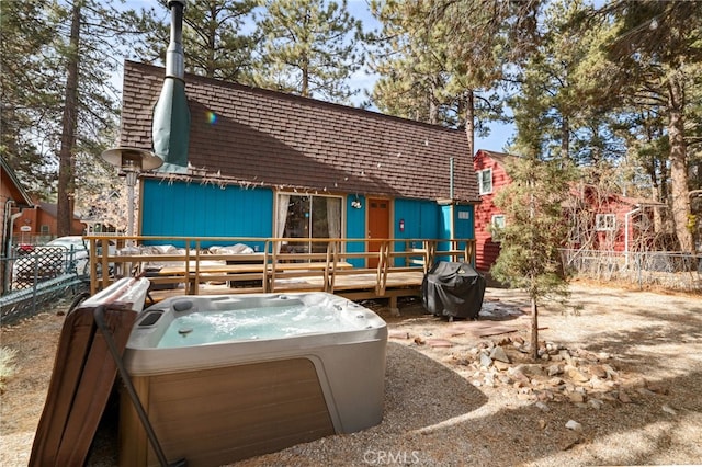 rear view of house with a wooden deck and a hot tub