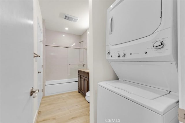 washroom with stacked washer / dryer and light wood-type flooring