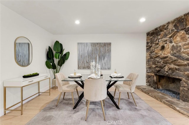 dining room featuring light wood-type flooring and a fireplace