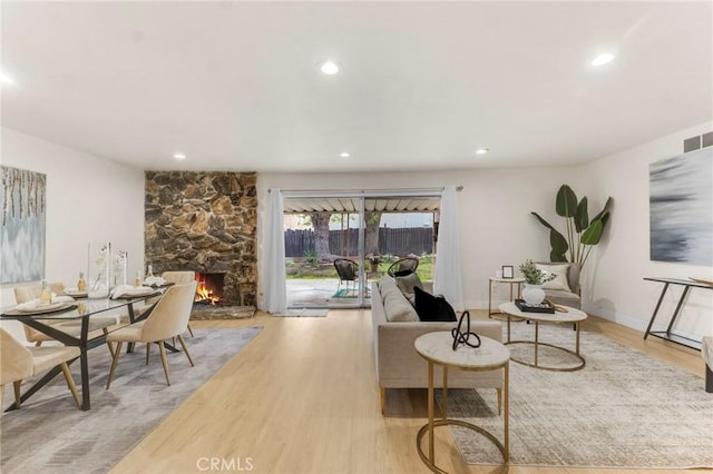 living room with light wood-type flooring and a stone fireplace