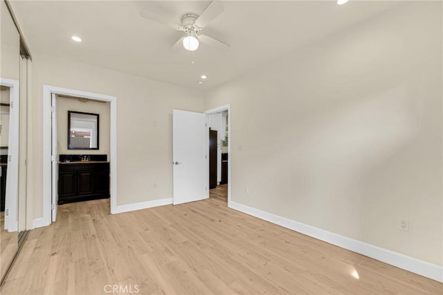 unfurnished bedroom with ceiling fan, connected bathroom, light hardwood / wood-style flooring, and black fridge