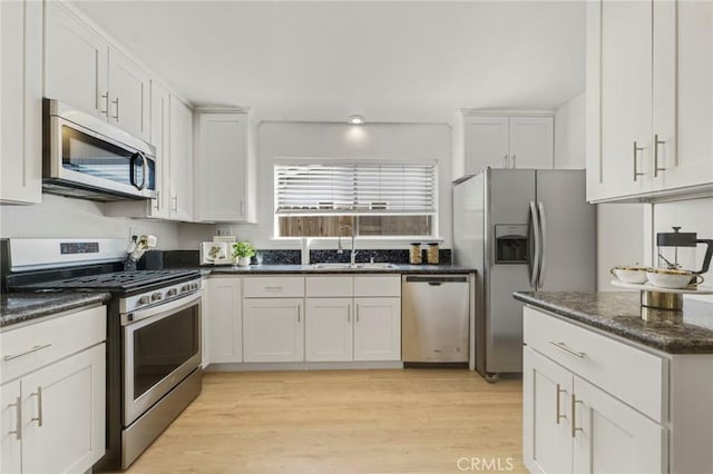 kitchen with sink, stainless steel appliances, white cabinetry, and light wood-type flooring