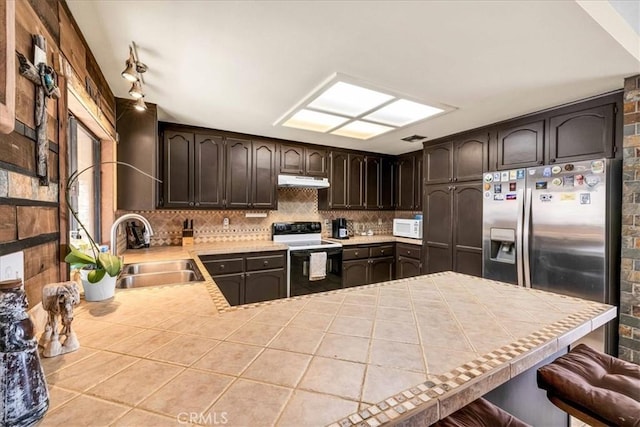 kitchen with tasteful backsplash, sink, dark brown cabinetry, electric range, and kitchen peninsula