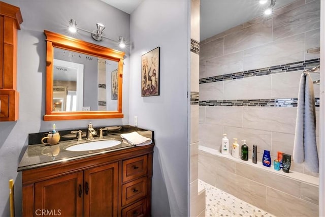 bathroom featuring tiled shower and vanity