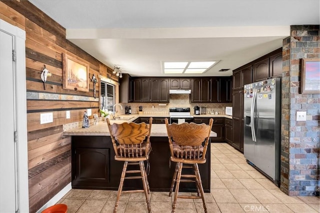 kitchen with decorative backsplash, a kitchen breakfast bar, black range with electric cooktop, kitchen peninsula, and stainless steel fridge