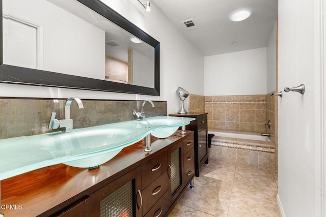 bathroom with vanity, a relaxing tiled tub, and tile patterned flooring