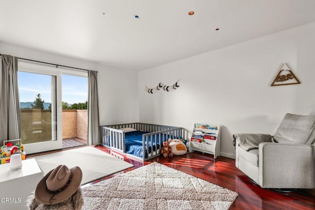 bedroom with wood-type flooring and a nursery area