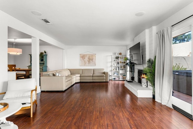 living room featuring a fireplace and dark wood-type flooring