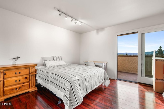 bedroom with hardwood / wood-style flooring, access to outside, and track lighting