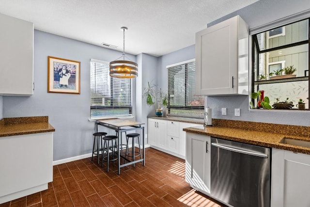 kitchen featuring white cabinetry, hanging light fixtures, dark stone countertops, and dishwasher