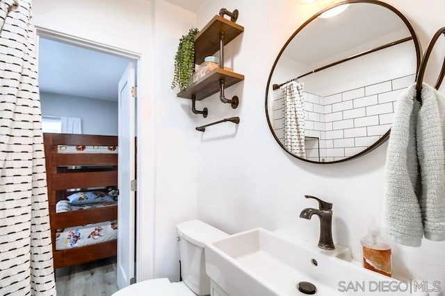 bathroom with hardwood / wood-style flooring, walk in shower, sink, and toilet