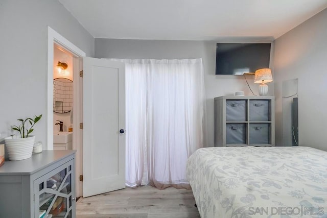 bedroom featuring connected bathroom and light wood-type flooring