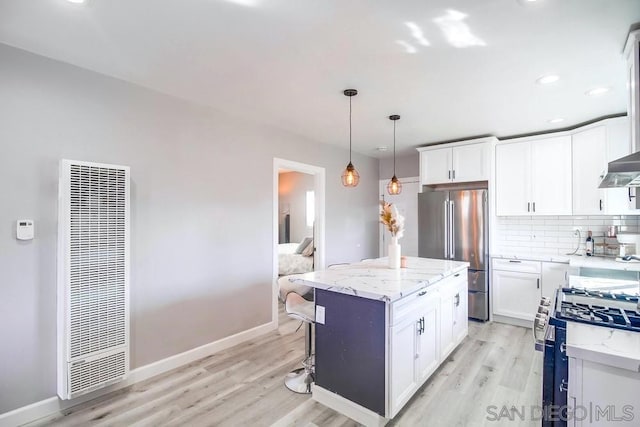 kitchen with appliances with stainless steel finishes, tasteful backsplash, white cabinetry, hanging light fixtures, and a center island