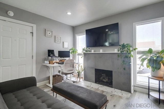 living room with a high end fireplace and light wood-type flooring