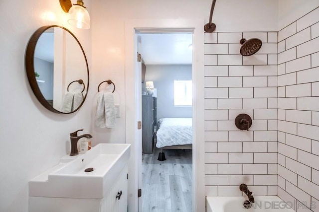 bathroom featuring hardwood / wood-style flooring, vanity, and tiled shower / bath