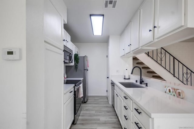 kitchen featuring light hardwood / wood-style floors, white cabinets, appliances with stainless steel finishes, and sink