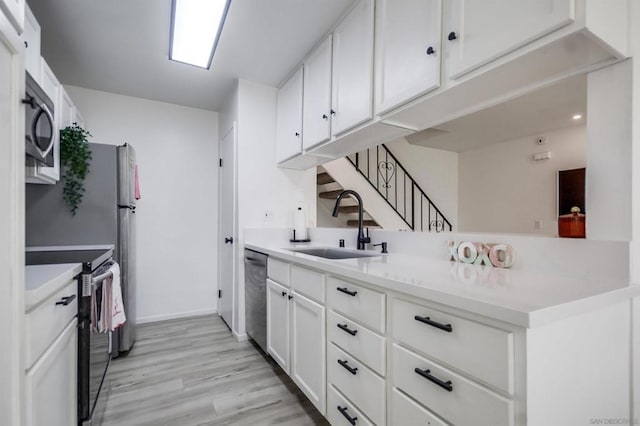 kitchen featuring white cabinets, stainless steel appliances, light hardwood / wood-style floors, sink, and kitchen peninsula