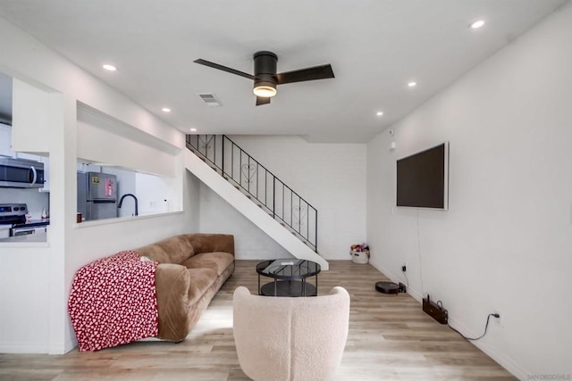 living room with sink, light hardwood / wood-style floors, and ceiling fan