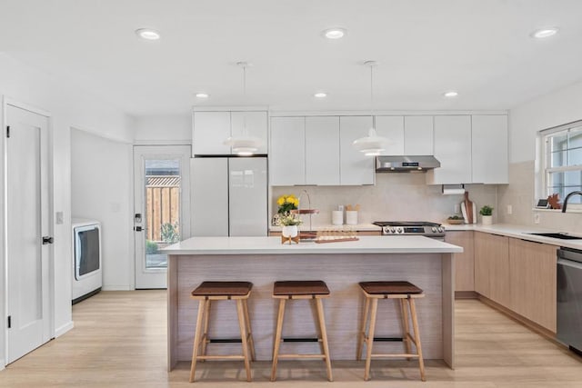 kitchen featuring decorative light fixtures, stainless steel appliances, a center island, and white cabinets