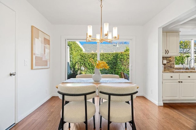 dining space with sink, a chandelier, and light wood-type flooring