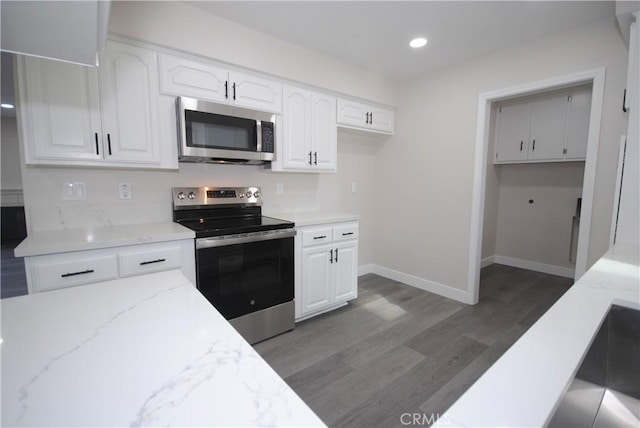 kitchen with light stone counters, white cabinets, dark hardwood / wood-style floors, and stainless steel appliances