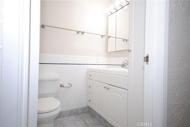 bathroom with tile walls, toilet, vanity, and tile patterned flooring