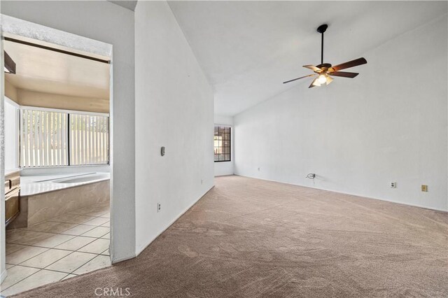 carpeted spare room featuring vaulted ceiling and ceiling fan