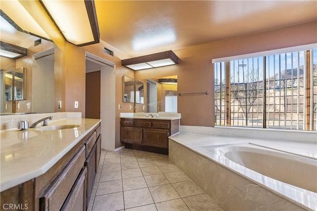 bathroom with vanity, a wealth of natural light, a bath, and tile patterned flooring