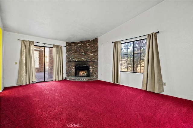 unfurnished living room with a brick fireplace, a wealth of natural light, carpet floors, and vaulted ceiling