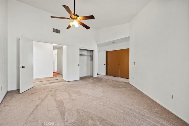 unfurnished bedroom with light colored carpet, high vaulted ceiling, and ceiling fan