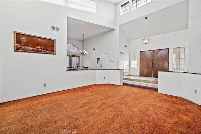 carpeted foyer with a towering ceiling, a chandelier, and a wealth of natural light