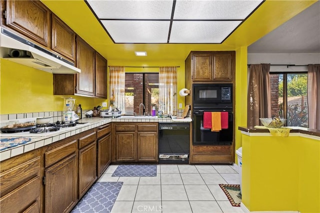 kitchen with sink, black appliances, tile countertops, and light tile patterned floors