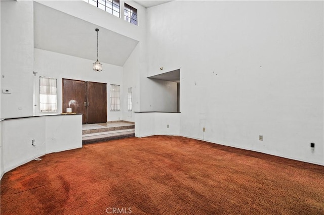 unfurnished living room featuring a high ceiling and carpet flooring