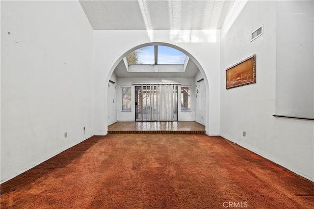 unfurnished living room featuring carpet floors, a towering ceiling, and a textured ceiling