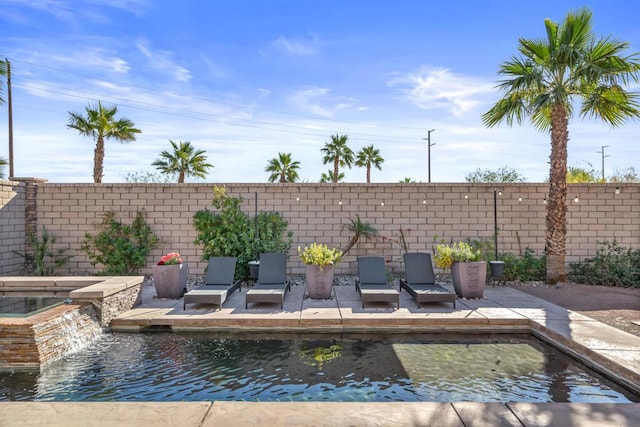 exterior space with an in ground hot tub, a patio area, and pool water feature