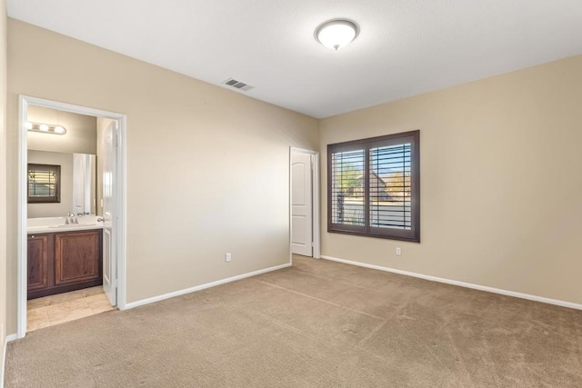 unfurnished bedroom with sink, ensuite bathroom, a closet, and light carpet