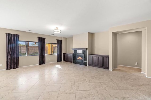 unfurnished living room with a tile fireplace and light tile patterned flooring