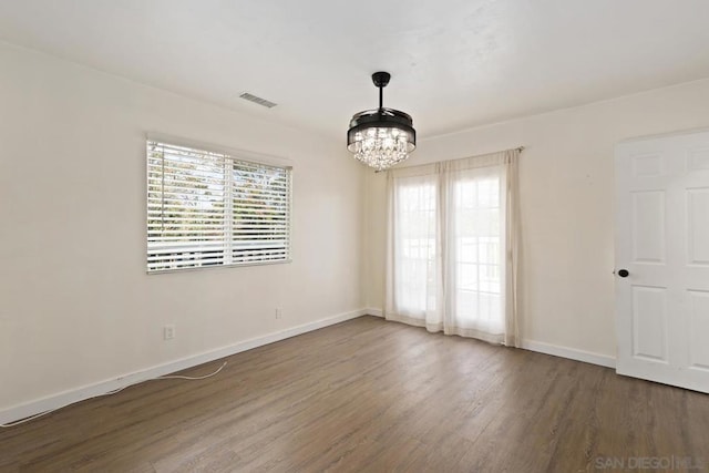 unfurnished room featuring an inviting chandelier and dark hardwood / wood-style floors