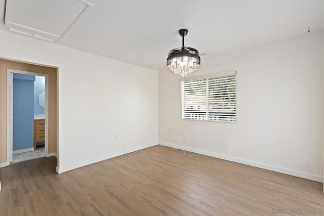 empty room with hardwood / wood-style floors and an inviting chandelier