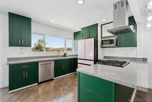 kitchen featuring light stone countertops, appliances with stainless steel finishes, green cabinetry, island range hood, and sink