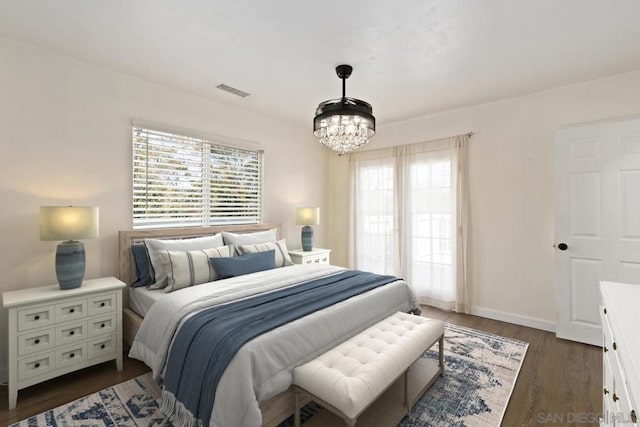 bedroom featuring dark wood-type flooring, multiple windows, and a chandelier