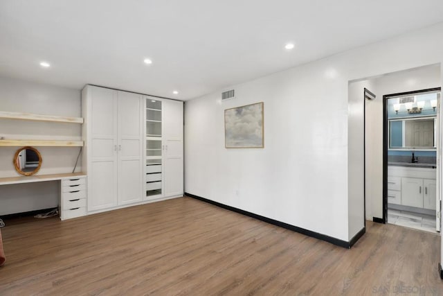 unfurnished office featuring sink, hardwood / wood-style floors, and built in desk