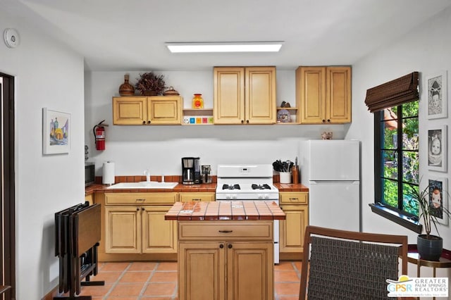 kitchen with sink, white appliances, light tile patterned floors, and tile counters