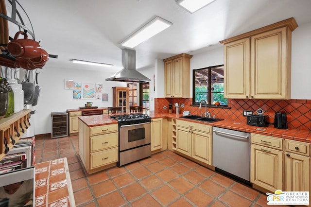 kitchen featuring kitchen peninsula, appliances with stainless steel finishes, sink, island exhaust hood, and tile countertops