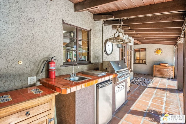 kitchen with fridge, tile counters, wooden ceiling, sink, and vaulted ceiling with beams